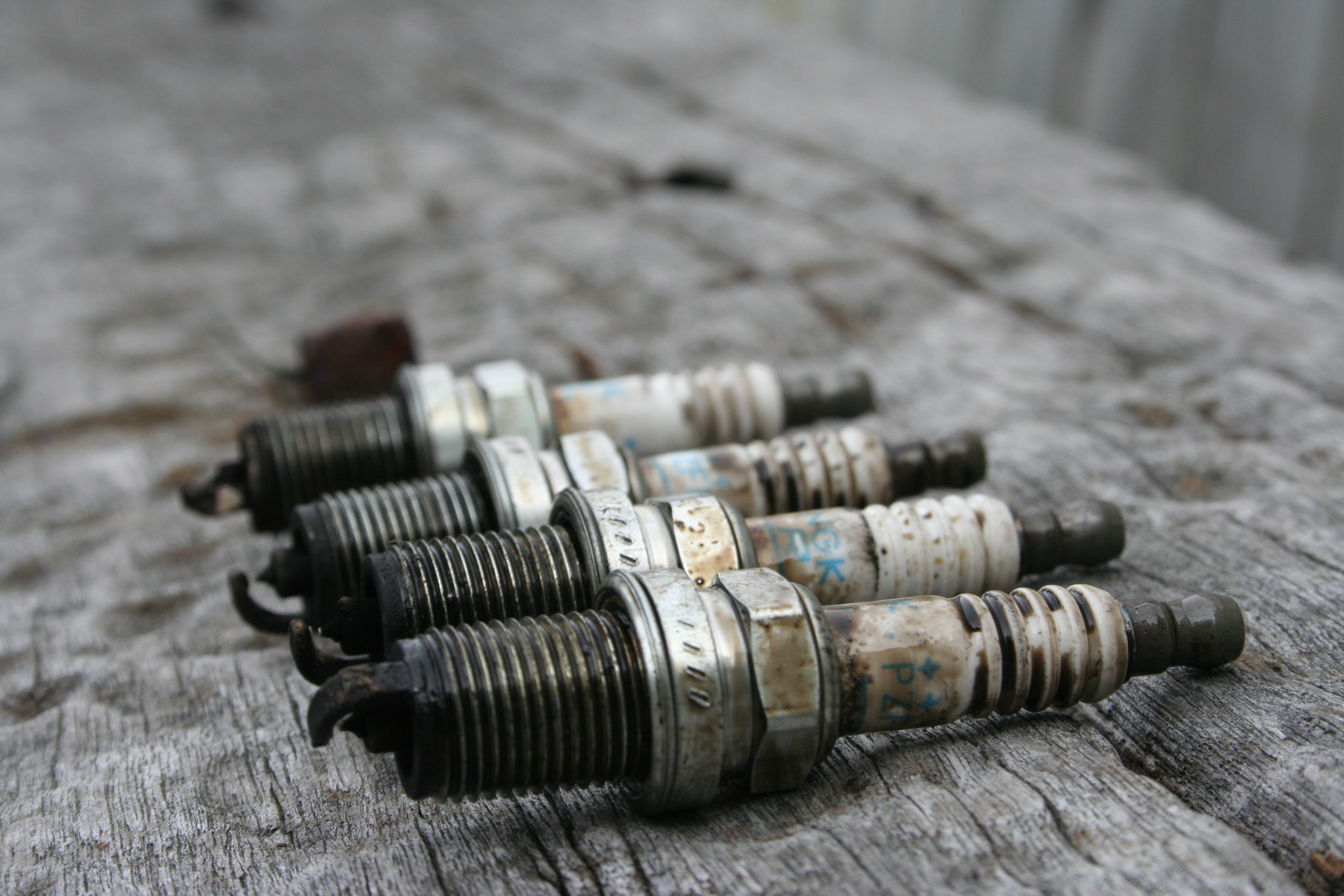 A group of automotive spark plugs on a workshop surface